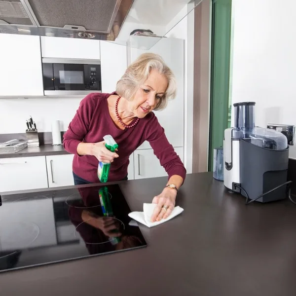 An elderly women using spring cleaning tips and tricks to clean her kitchen