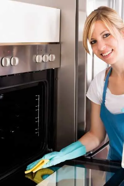 a woman cleaning oven with homemade oven cleaner