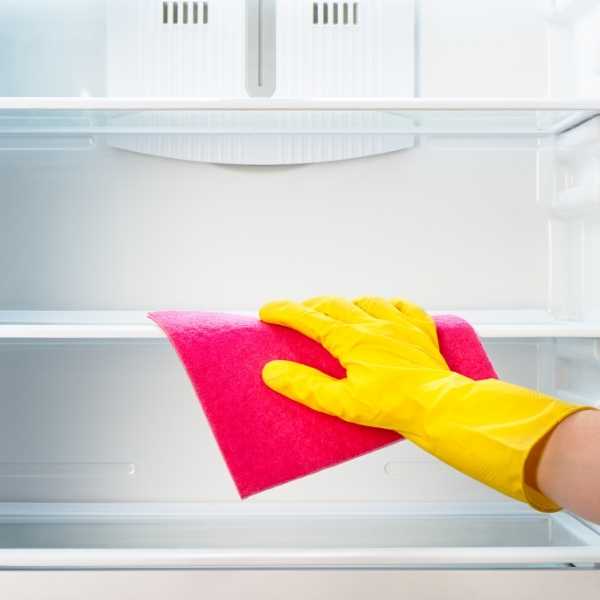 A hand cleaning a refrigerator