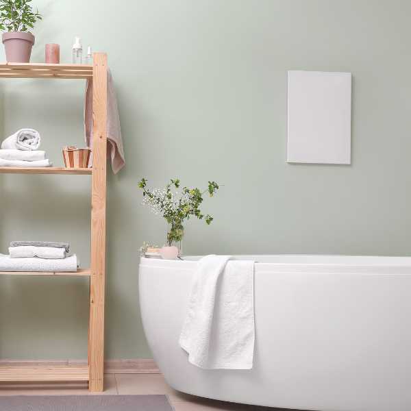 White bathtub and towel ladder against pearl gray wall.