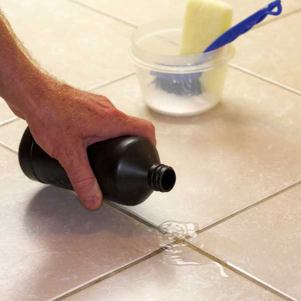 Someone pouring peroxide on grout.
