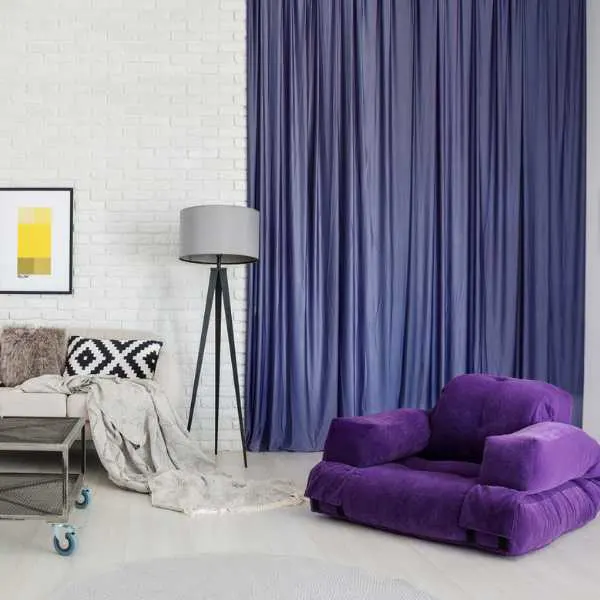 Living room with indigo curtain and purple couch.