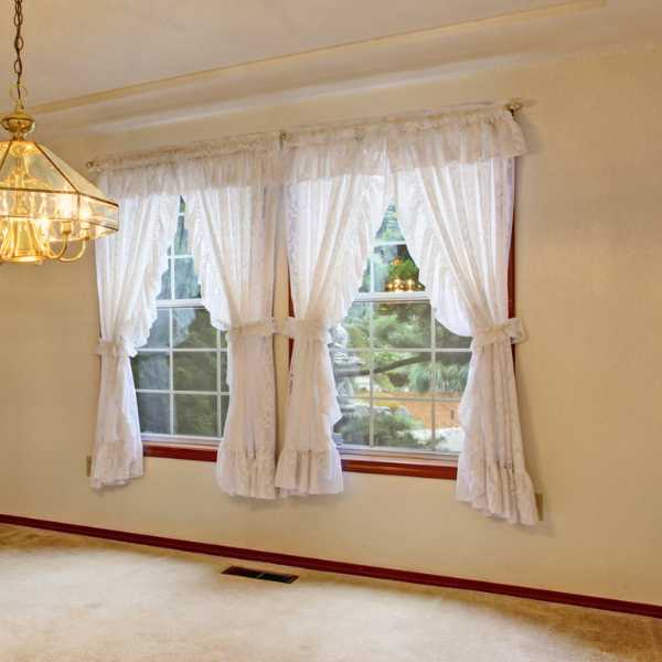 Room with beige walls and white curtains.