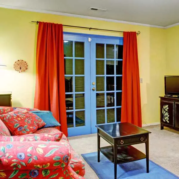 Living room with yellow wall red curtains blue doors.