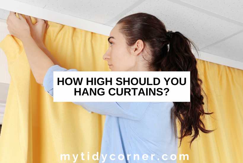A woman hanging a yellow curtain and text overlay that reads, "How high should you hang curtains".