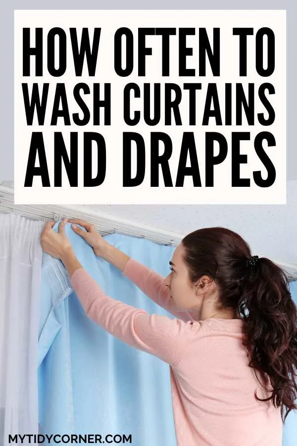 Woman hanging a blue curtain and text overlay that reads, "How often to wash curtains and drapes".