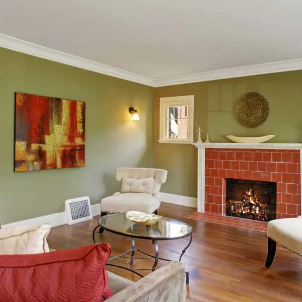 Living room with sage green walls and white ceiling, brick fireplace and furniture.