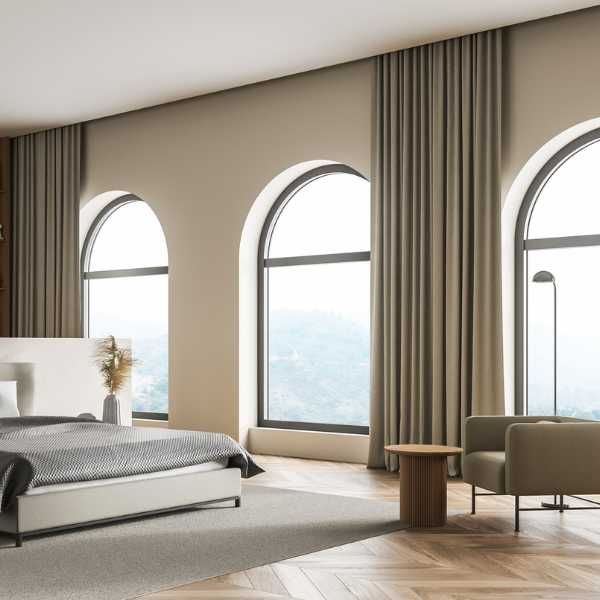 Room with arched windows and ceiling high curtains.