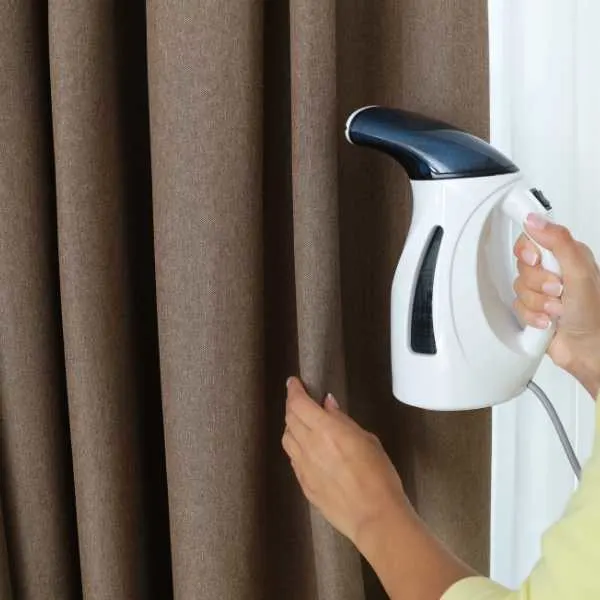 Woman steam cleaning curtain.