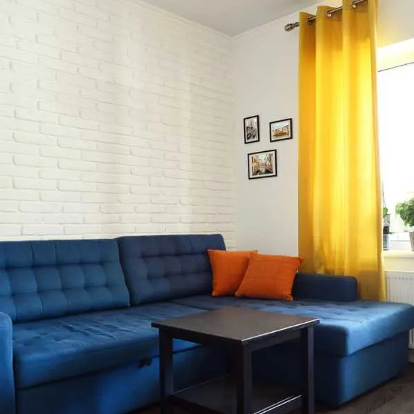 Blue sofa orange pillows and yellow curtain.
