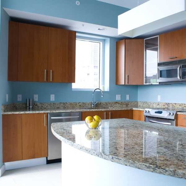 Modern kitchen with sky blue walls brown, brown cabinets and granite countertops.