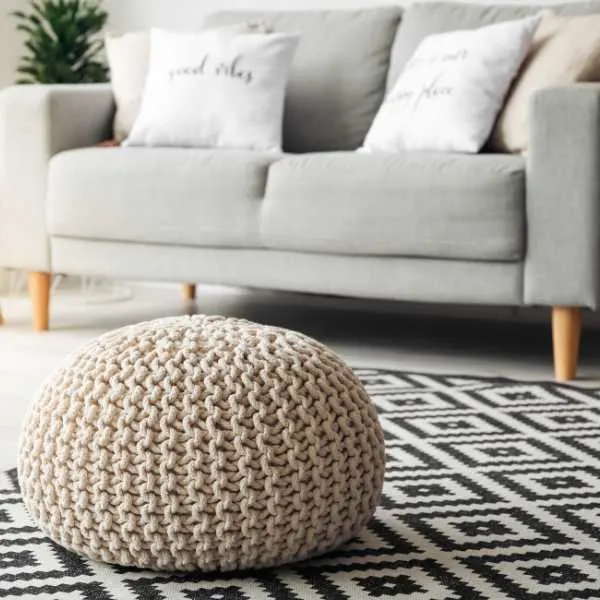 Throw pillows on couch and ottoman on black and white rug.