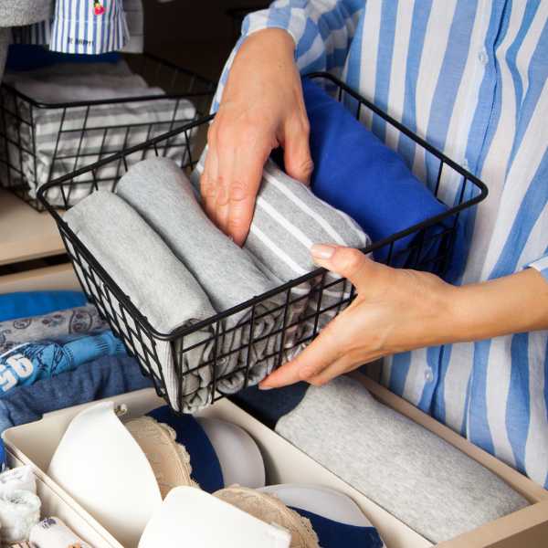 Woman putting folded clothes in a wire organizer.