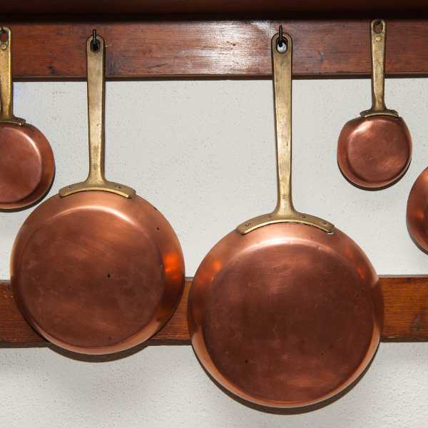 Copper cookware hanging on a wall.
