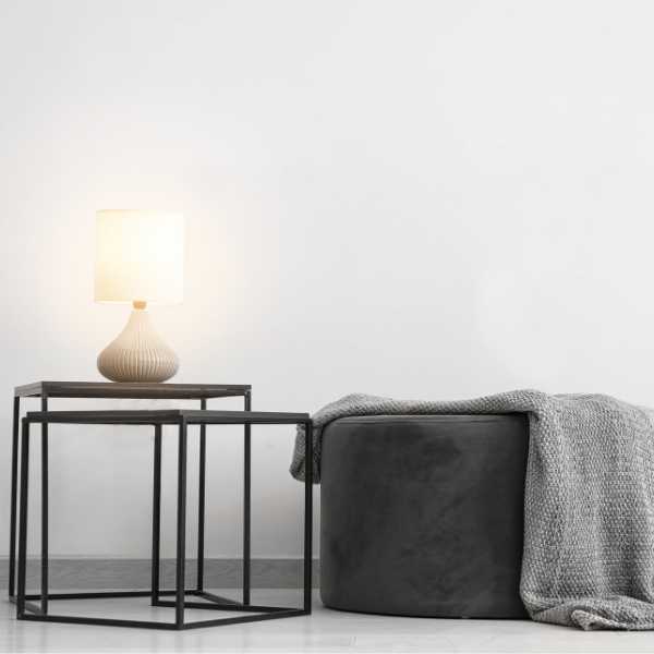 Lamp on a side table and throw on a pouf.