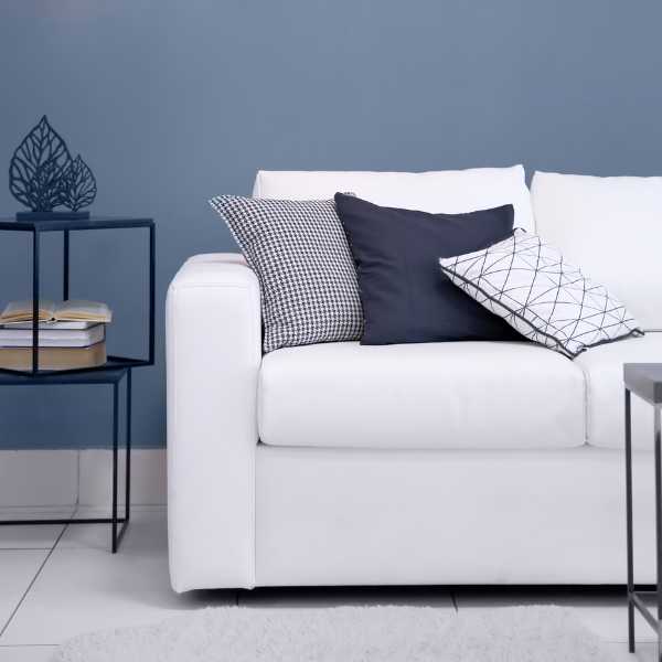 Throw pillows on white couch and grayish blue wall.