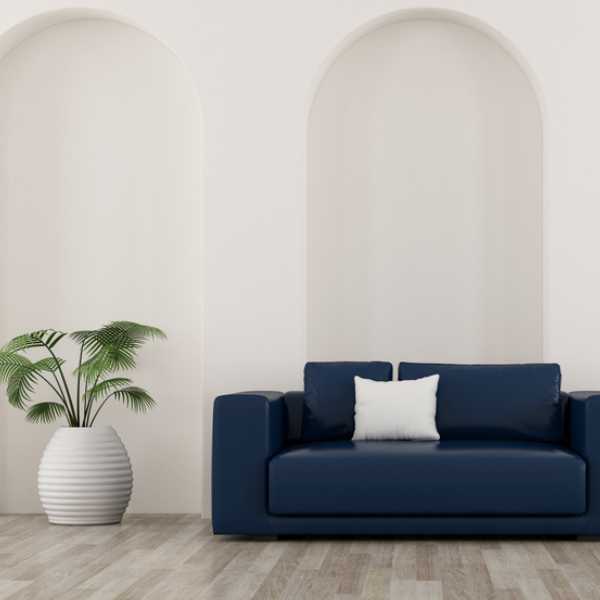 Navy blue couch, potted plant, neutral wall.