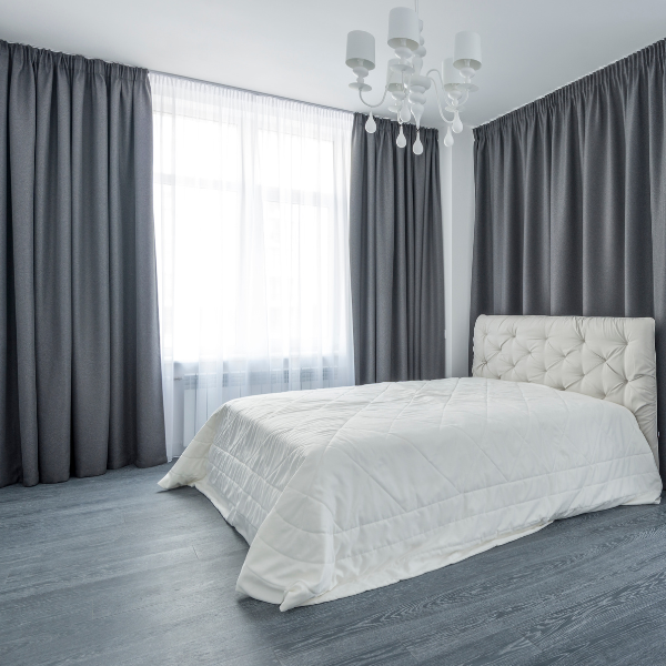 Bedroom with gray curtains and white bedding.