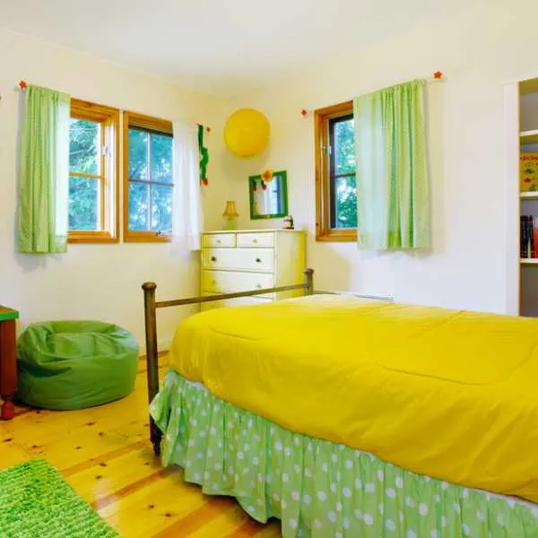 Colorful kids bedroom with green curtains and yellow bedding.