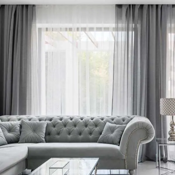 Living room with gray couch and curtains.
