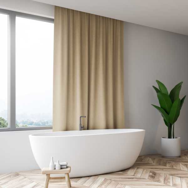Modern bathroom with beige curtain, bathtub and plant.