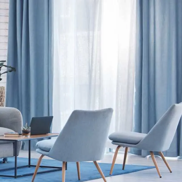 Room with blue and white curtains, gray chairs and blue rug.