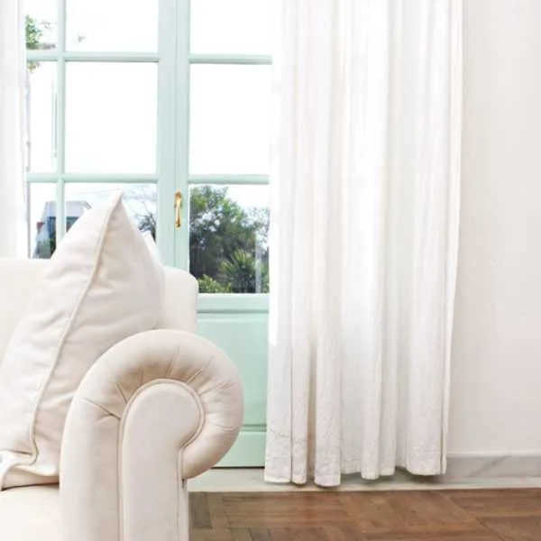 Room with white couch and curtain.