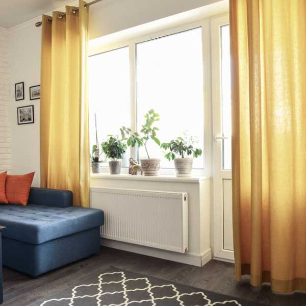 Room with yellow curtains and blue couch.