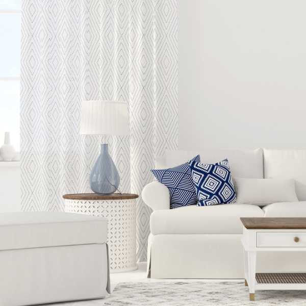 Living room with white couch, blue and white throw pillows and white curtain.