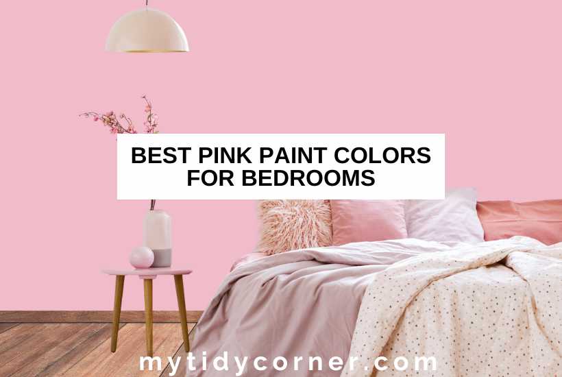 Room with pink wall background and wood floor, bed, assorted colors of pillows, flower vase on a stool, overhead lamp and text overlay that says, "Best pink paint colors for bedrooms".