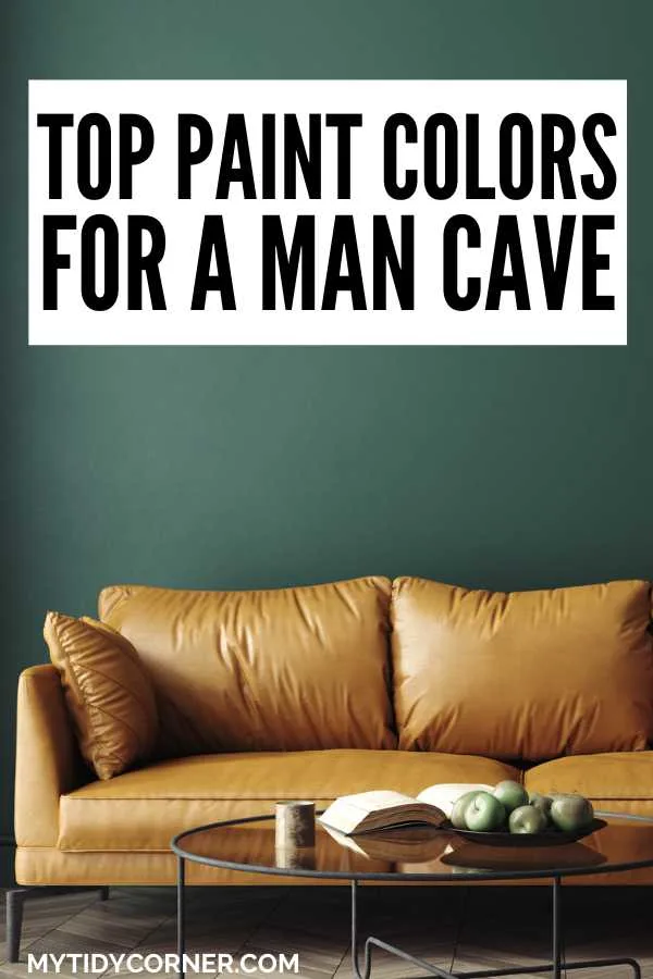 Book and fruit on a coffee table, light brown couch, green wall background and text overlay that says, "Top paint colors for a man cave".