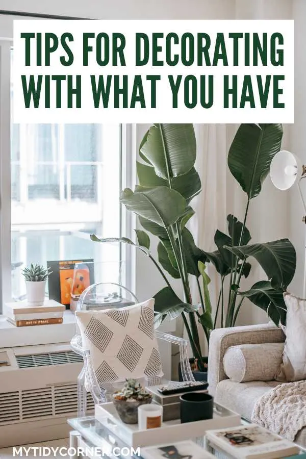 Small living room with a large plant and text overlay that says, "Tips for decorating with what you have".