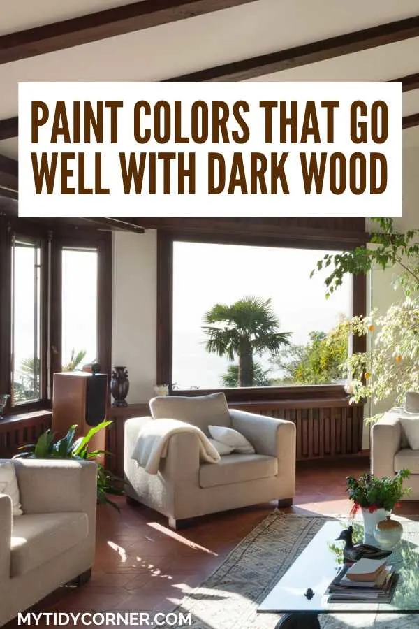 Modern living room with white chairs and wood trims and text overlay that says, "Paint colors that go well with dark wood".